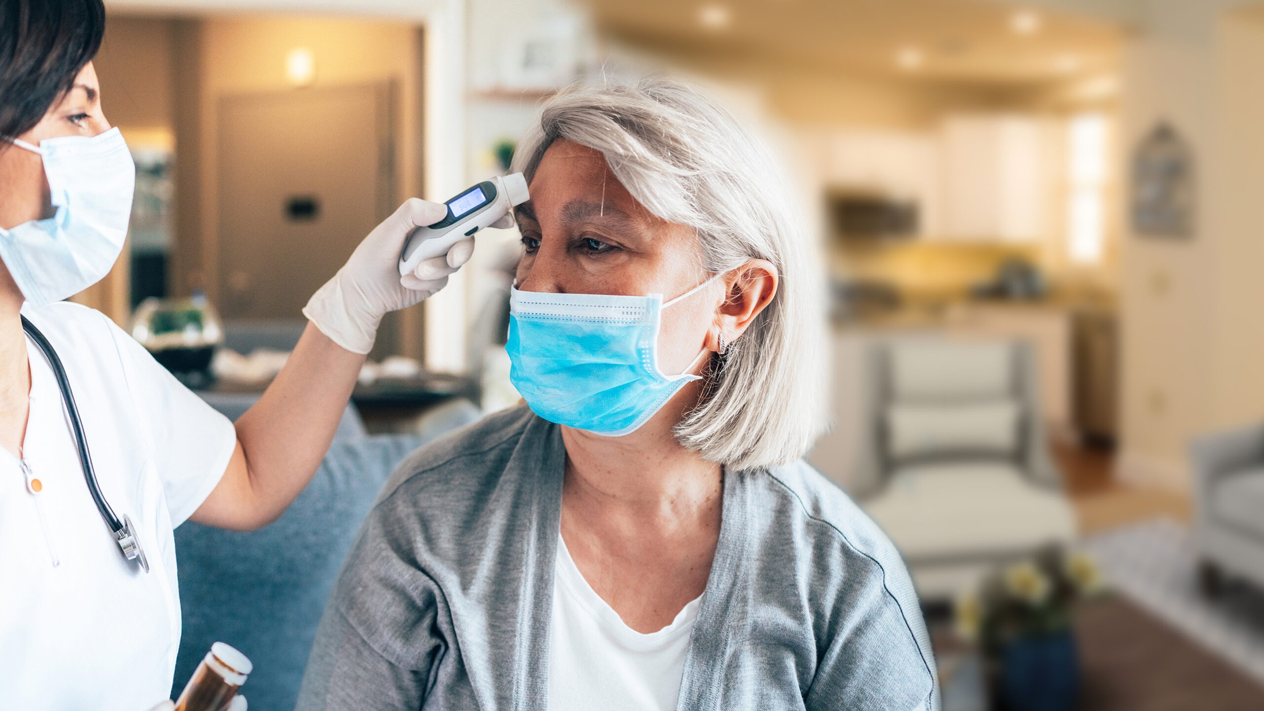 Nurse taking a residents temperature wearing masks